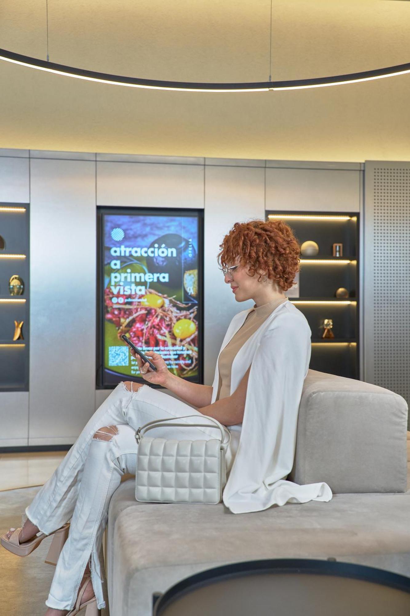 Pullman Santiago Vitacura 외부 사진 A woman using a mobile phone to interact with a digital signage display