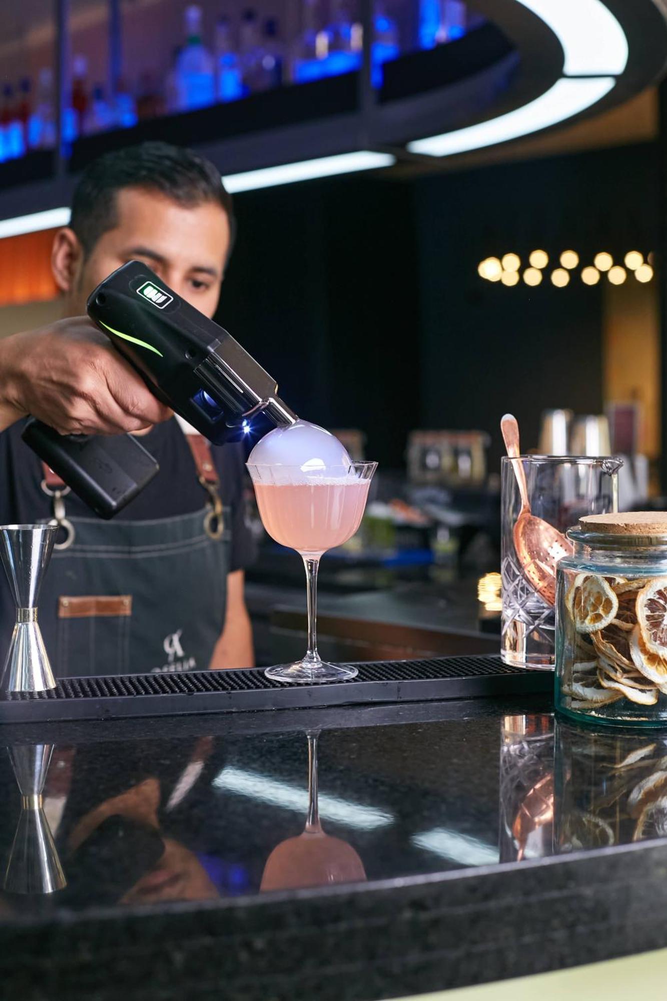 Pullman Santiago Vitacura 외부 사진 A bartender using a blowtorch to cook a cocktail
